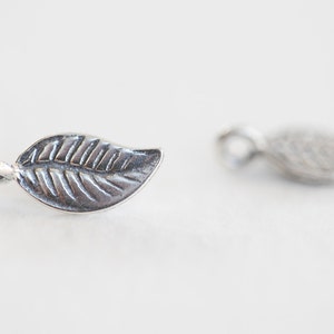 May include: Two silver leaf charms with a loop for attaching to jewelry or other crafts.