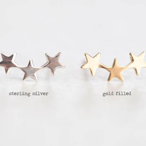 May include: Two pairs of star-shaped earrings, one pair in sterling silver and one pair in gold filled. The earrings are in the shape of three stars connected together.