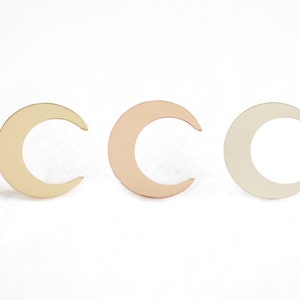 May include: Three crescent moon shapes in different metal finishes: gold, rose gold, and silver.
