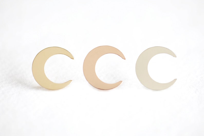 May include: Three crescent moon shapes in different metal finishes: gold, rose gold, and silver.