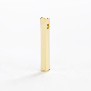 May include: A gold-colored metal bar with a hole in the center. The bar is about 1 inch long and 1/4 inch wide.