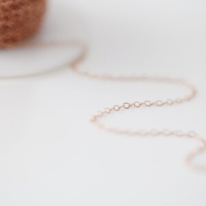 Op de afbeelding: Een close-up van een ros&eacute;gouden kettingketting. De ketting is gemaakt van kleine, delicate schakels.
