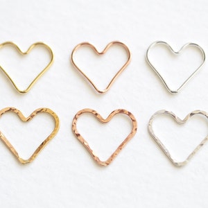 May include: Six heart-shaped wire hoops in different finishes: gold, rose gold, and silver. The hoops are smooth and have a delicate, feminine look.