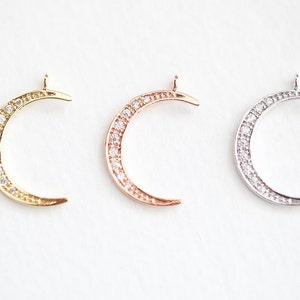 May include: Three crescent moon charms with a pave setting of clear cubic zirconia stones. The charms are available in gold, rose gold, and silver.
