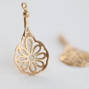 May include: A pair of gold-tone filigree earrings with a flower design. The earrings are marked "925" on the back.
