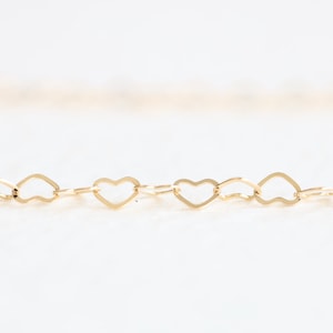 May include: A gold chain necklace with a heart-shaped link design.