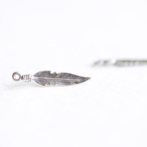May include: A silver feather charm with a loop at the top for attaching to jewellery or other crafts.