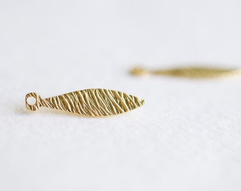 May include: A gold-coloured metal leaf charm with a textured surface and a small loop at the top.