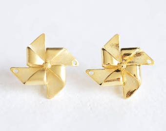 May include: A pair of gold-colored metal earrings shaped like pinwheels. Each earring has five points and a small hole in the center.
