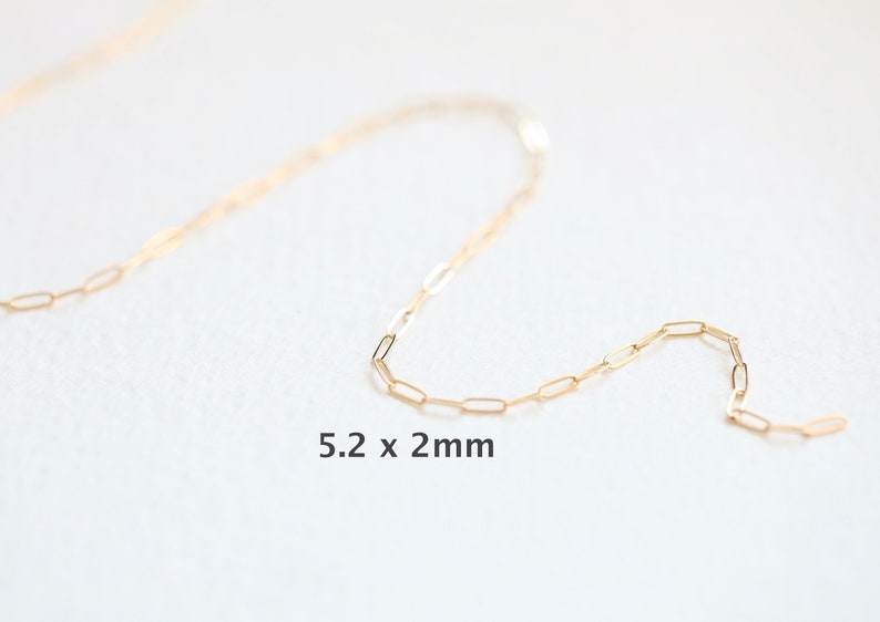May include: A gold chain necklace with a delicate, rectangular link design. The chain is 5.2 x 2 mm in size.