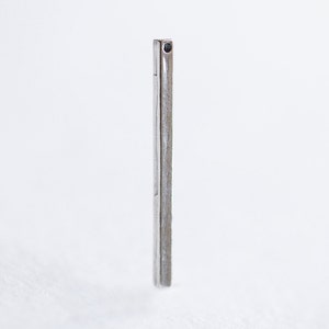 May include: A silver bar earring with a small black gemstone at the top.