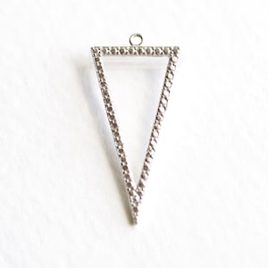 May include: A silver triangle pendant with a textured border. The pendant has a loop at the top for attaching to a chain.