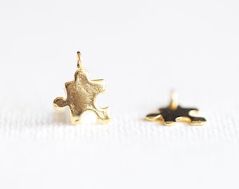 May include: Two gold-colored puzzle piece charms. The charms are small and have a smooth, shiny finish.