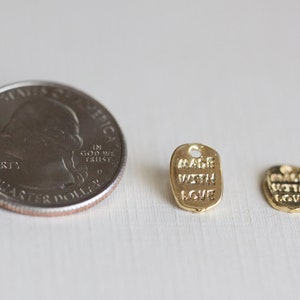 May include: Two gold-colored metal tags with the text "Made with Love" on them. The tags are about the size of a US quarter.
