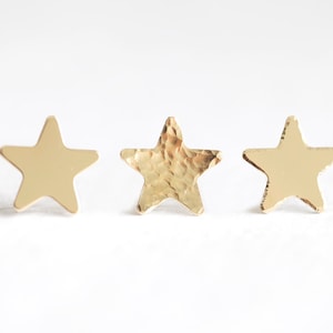 Puede incluir: Tres pendientes de estrella de oro. El pendiente del medio tiene una textura martillada.