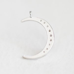 May include: A silver crescent moon charm with small clear stones set around the edge.