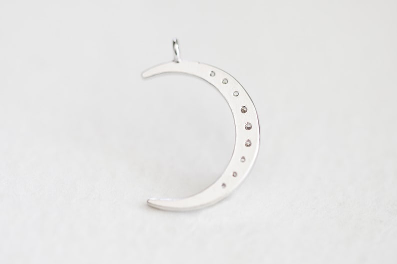 May include: A silver crescent moon charm with small clear stones set around the edge.