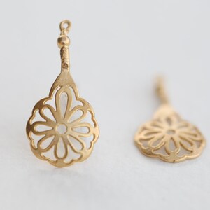 May include: A pair of gold-tone dangle earrings with a delicate, openwork flower design.
