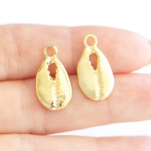 May include: Two gold-colored shell charms with a hole at the top for attaching to jewelry or other crafts.