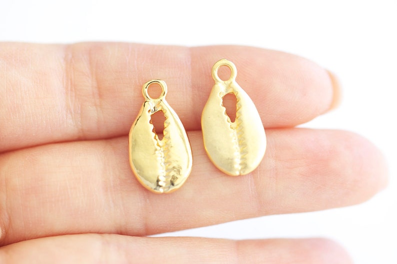 May include: Two gold-colored shell charms with a hole at the top for attaching to jewelry or other crafts.