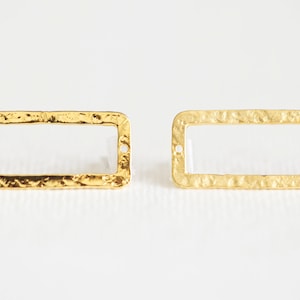 May include: Two gold-toned rectangular metal frames with a hammered texture. The frames have two small holes on each side.