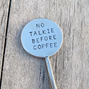 May include: A silver metal stirring spoon with the text "NO TALKIE BEFORE COFFEE" engraved on the handle.