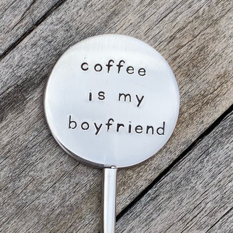 May include: A silver metal spoon with a round, flat handle that says "coffee is my boyfriend".