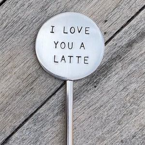 May include: A silver metal stirring spoon with a round handle that says "I love you a latte".