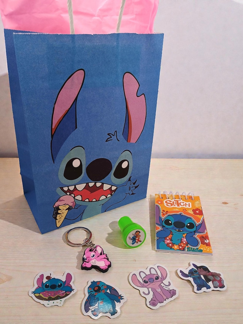 May include: A blue paper gift bag featuring a cartoon character eating ice cream. The image also shows a keychain, stickers, a stamp, and a notepad, all with the same cartoon character theme. The items are arranged on a light-colored surface.