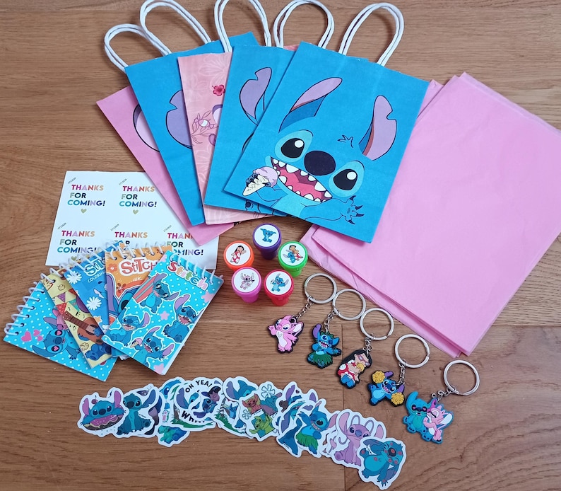 May include: A collection of Stitch-themed party supplies, including blue and pink gift bags, stickers, stamps, keychains, and notepads. The gift bags feature Stitch's face. A sheet of paper reads "Thanks for coming!"