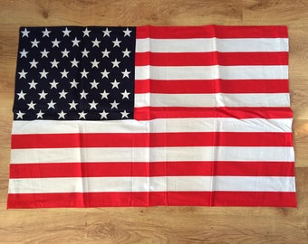 Könnte beinhalten: Eine gefaltete amerikanische Flagge mit roten und weißen Streifen und einem blauen Sternenfeld.