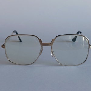 Op de afbeelding: Zilveren bril met heldere glazen. Het montuur heeft een geometrische vorm met een licht vierkante vorm.