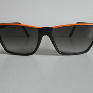 Puede incluir: Gafas de sol negras con un borde naranja alrededor de las lentes.