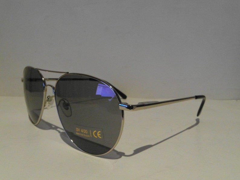 K&ouml;nnte beinhalten: Silberne Aviator-Sonnenbrille mit dunkelgrauen Gl&auml;sern. Die Sonnenbrille hat UV 400 Schutz und CE-Zertifizierung.