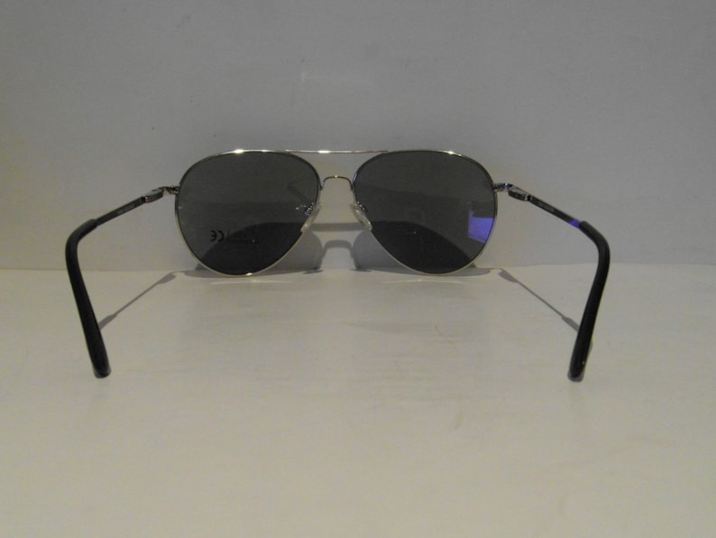 K&ouml;nnte beinhalten: Silberne Aviator-Sonnenbrille mit dunkelgrauen Gl&auml;sern. Die Sonnenbrille hat einen schwarzen Rahmen und wird von hinten gezeigt.