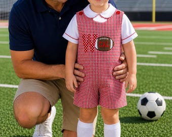 May include: A red and white gingham overall short set featuring a white collared shirt underneath. The overall front displays a large letter W and a brown football applique with the text CAL embroidered in red on the football surface.