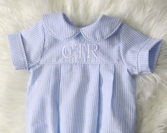 May include: A blue and white striped baby onesie with a white peter pan collar and the letters "CTR" embroidered on the front.