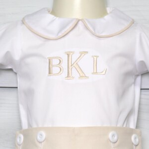 May include: White long-sleeve shirt with a beige collar and cuffs. The shirt has a beige embroidered monogram "BKL" on the front.