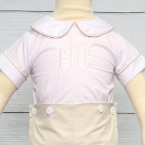 May include: A white short-sleeved button-down shirt with a tan collar and cuffs. The shirt has a tan trim around the collar and cuffs. The shirt is embroidered with the letters "TRC" in tan thread. The shirt is paired with tan shorts.