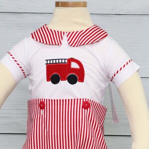 May include: A white and red striped short-sleeved outfit with a red fire engine appliqu&eacute;. The outfit has a sailor collar and red buttons.