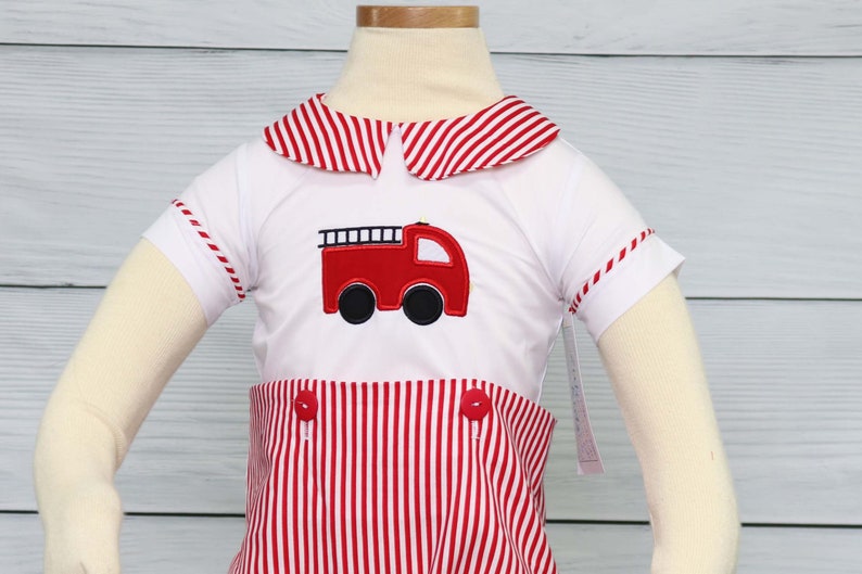 May include: A white and red striped short-sleeved outfit with a red fire engine appliqu&eacute;. The outfit has a sailor collar and red buttons.