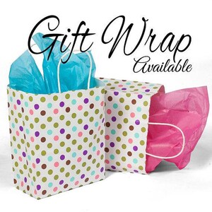 May include: Two gift bags with white handles and polka dots in various colors. One bag contains blue tissue paper, and the other contains pink tissue paper. The text "Gift Wrap Available" is written in black cursive.