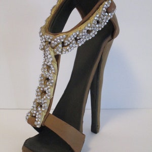 May include: A brown high-heeled sandal with a gold and silver embellished strap.