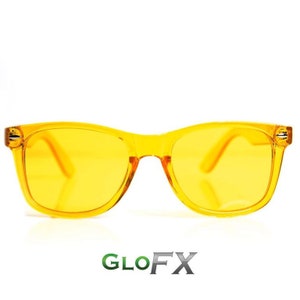 Puede incluir: Un par de gafas de sol de color amarillo con montura negra. Las gafas de sol son de plástico y tienen un estilo aviador clásico.