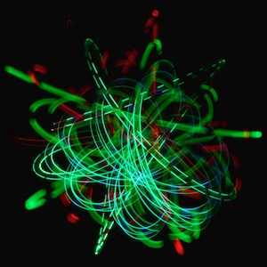 Puede incluir: Arte abstracto creado con trazos de luz verde y roja sobre un fondo negro.