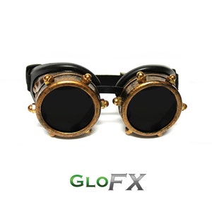 May include: Steampunk goggles with black lenses and a distressed bronze finish. The round frames are accented with gold-coloured rivets and trim. A black leather strap connects the two lenses, and the logo "GLO FX" is at the bottom.