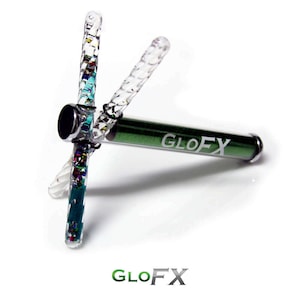 Könnte beinhalten: Ein transparentes Plastikspielzeug mit buntem Glitzer im Inneren und einem grünen Rohr mit dem aufgedruckten Wort "GLOFX".