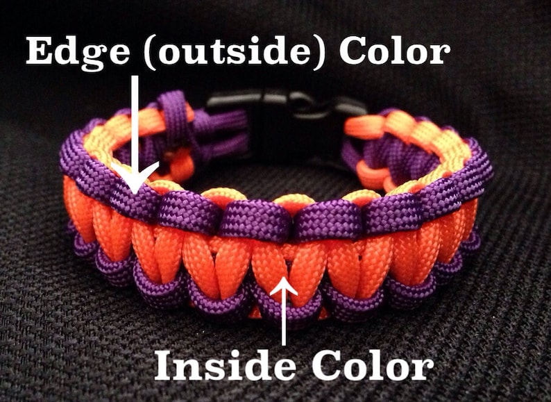 May include: A two-tone paracord bracelet with an orange edge (outside) color and a purple inside color. The bracelet is made with a woven pattern and has a black plastic clasp.