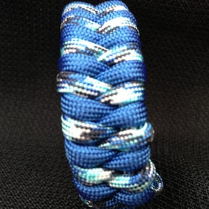 May include: A blue and white paracord bracelet with a braided pattern.