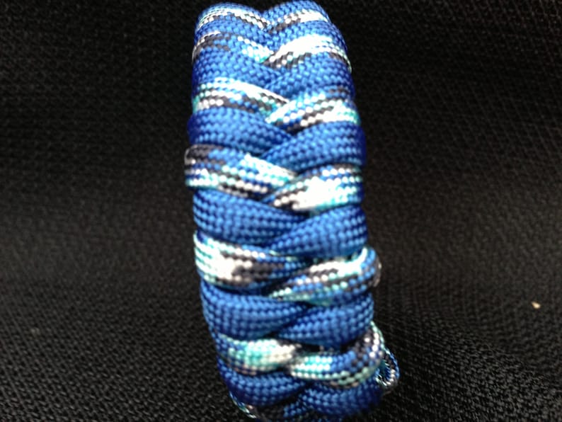 May include: A blue and white paracord bracelet with a braided pattern.